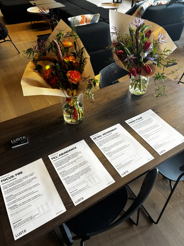Two finished bouquets in glass vases beside printed station cards guiding participants through each arranging step