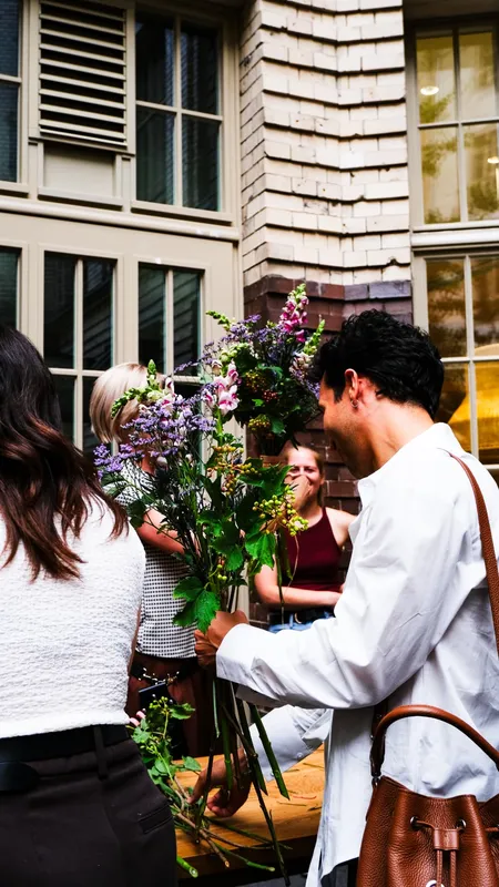 Colleagues gathered in a courtyard comparing freshly wrapped bouquets during an outdoor pop-up flower bar