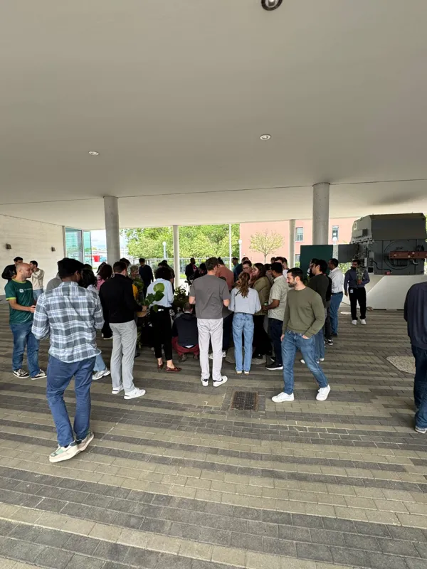 A large crowd of employees gathered around a plant pop-up stand in a covered outdoor walkway